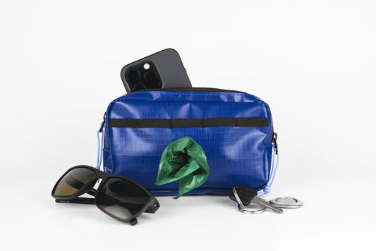 Blue Phone Pouch with built-in poop bag dispenser, holding a phone, keys, and sunglasses.