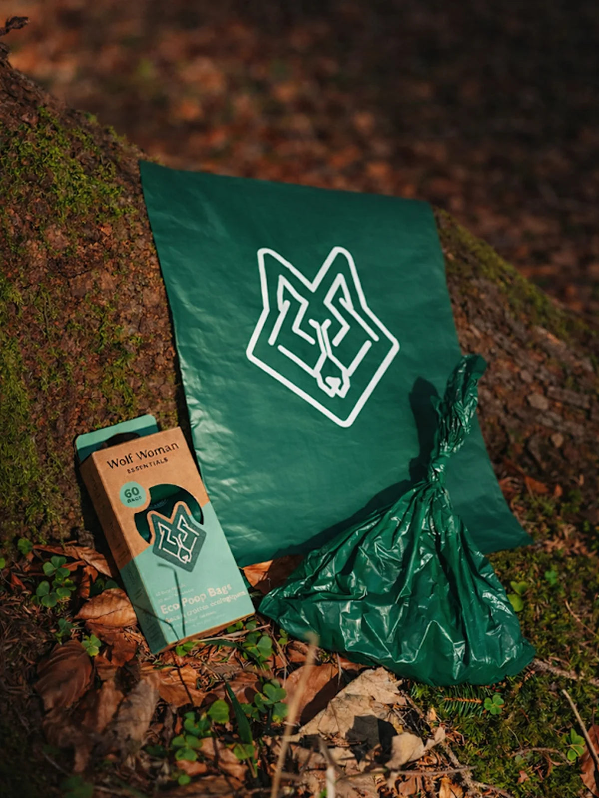 Wolf Woman Essentials eco poop bags made from 65% post-consumer recycled plastic, displayed outdoors on forest floor