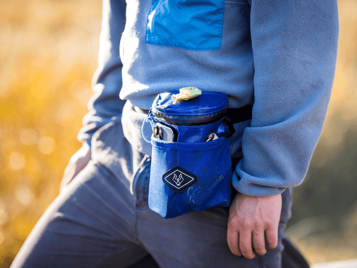 Dog owner wearing Wolf Woman Essentials blue Waste Wrangler treat and waste bag pouch on waist during outdoor walk